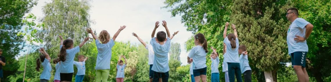 Group of children with instructor doing exercises in a sunny park setting, promoting outdoor activity.